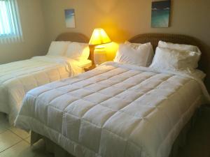 Duas camas num quarto de hotel com um edredão branco em Ocean Beach Villas Unit 302- Direct Oceanfront Condo! em Cocoa Beach