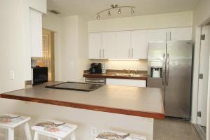 a kitchen with white cabinets and a stainless steel refrigerator at NEW! 219 Garfield Ave in Cocoa Beach