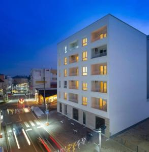 a tall white building with lights on in a city at Apartman Sisters in Sanski most