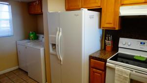 - un réfrigérateur blanc dans une cuisine avec des placards en bois dans l'établissement Spanish Main 63- Rare Direct Oceanfront 3 BR Condo!, à Cocoa Beach