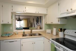 a kitchen with white cabinets and a sink at WOW! Updated Oceanfront, Pool Front Spanish Main Condo 45! in Cocoa Beach