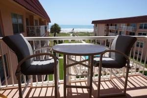 a table and two chairs on a balcony with the beach at WOW! Updated Oceanfront, Pool Front Spanish Main Condo 45! in Cocoa Beach