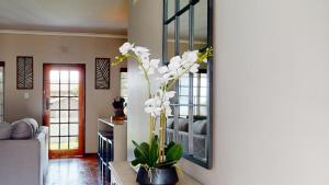 uma sala de estar com um vaso com flores brancas em Seas the day Scottburgh by Top Destinations Rentals em Scottburgh