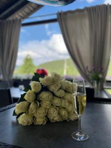 a bouquet of white roses next to a glass of wine at Lastivka Guest House in Yablunytsya
