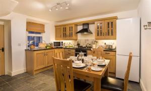 a kitchen with a wooden table with chairs and a kitchen with at The Cats Bield in Keswick