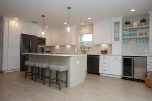 a kitchen with white cabinets and a island with bar stools at 213 Grant Ave in Cocoa Beach