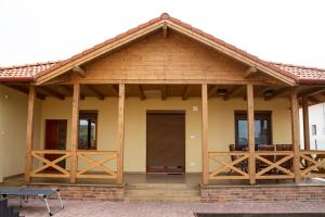 a house with a wooden roof and a porch at Szélrózsa Vendégház Demjén in Demjén