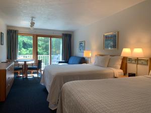 a hotel room with two beds and a table and chairs at AppleCreek Resort-Hotel & Suites in Fish Creek