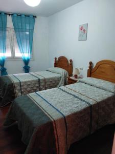 ビラガルシーア・デ・アロウサにあるPiso en Villagarcia de Arosaの青いカーテン付きの部屋のベッド3台