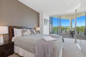 1 dormitorio con 1 cama grande y balcón en Cotton Beach Resort - Tweed Coast Holidays ® en Kingscliff