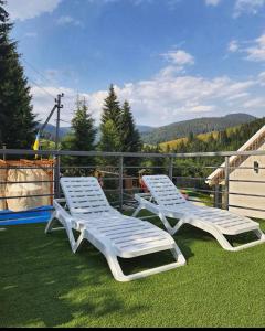 two white lounge chairs sitting on top of the grass at Lastivka Guest House in Yablunytsya