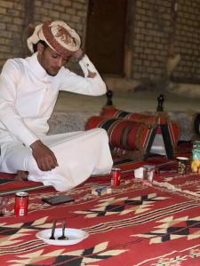 a man sitting on a bed with a plate of food at Little Petra Heritage Village in Wadi Musa