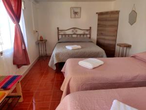 a hotel room with two beds and a window at Pirca Hostal in San Pedro de Atacama