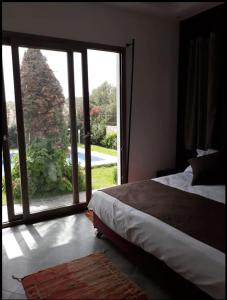 Schlafzimmer mit einem Bett und einer großen Glasschiebetür in der Unterkunft Villa Toufitri in Agadir