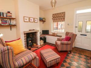 a living room with two chairs and a fireplace at Mill Cottage in Leek