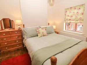 a bedroom with a bed with a dresser and a window at Mill Cottage in Leek