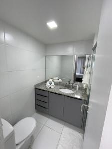 a white bathroom with a toilet and a sink at Paraíso à sua Porta Ap Luxuoso Prédio Frontal Mar in Rio de Janeiro