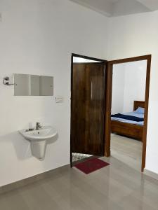 a bathroom with a sink and a bedroom with a bed at Wayanad Biriyomz Residency, Kalpatta, Low Cost Rooms and Deluxe Apartment in Kalpetta
