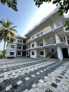 a large white building with a palm tree in the foreground at Wayanad Biriyomz Residency, Kalpatta, Low Cost Rooms and Deluxe Apartment in Kalpetta