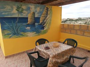 a table with chairs and a painting on the wall at Il Sole Di Lampedusa in Lampedusa