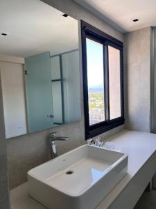 La salle de bains est pourvue d'un grand lavabo blanc et d'une fenêtre. dans l'établissement Nuevo Hotel Ancasti, à San Fernando del Valle de Catamarca