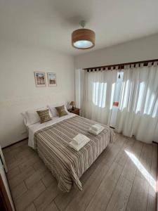 Habitación blanca con cama grande con almohadas en Depto Barrio La Perla en Mar del Plata