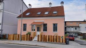 a small pink house with a wooden fence at Ferienwohnung Christa in Graz