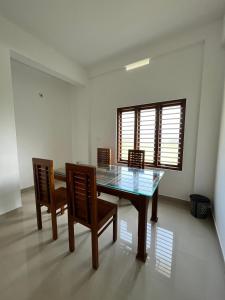 a dining room with a glass table and chairs at Wayanad Biriyomz Residency, Kalpatta, Low Cost Rooms and Deluxe Apartment in Kalpetta