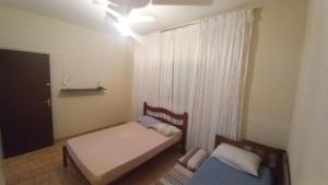 a small bedroom with two beds and a window at Residência Manto Azul in Aparecida