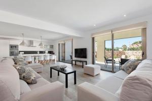 a living room with a white couch and a kitchen at VILLA NOKA in Cala en Blanes