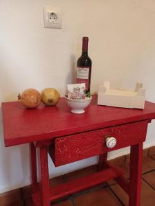 una mesa roja con una botella de vino y dos verduras en Alojamientos Cabezo del Gato, en Aracena