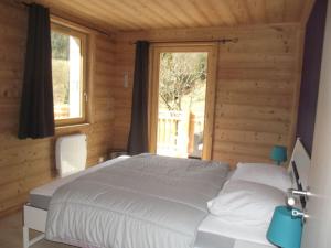 1 dormitorio con cama blanca y ventana en location appartement pied des pistes, en La Bresse