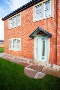 a brick house with a blue door in the grass at Luxury House in Clitheroe in Clitheroe