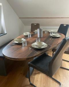 a wooden table with chairs and plates on it at FederKern Simonskall in Hürtgenwald