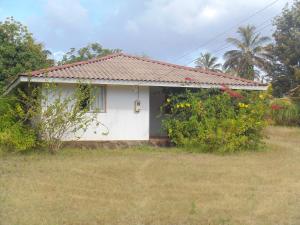 a small white house with a garden at Cabañas Varua in Hanga Roa