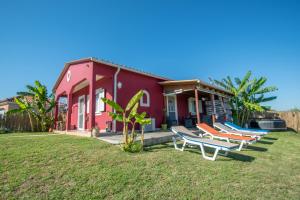 a pink house with lounge chairs in front of it at Konstantinos holidays house in Laganas