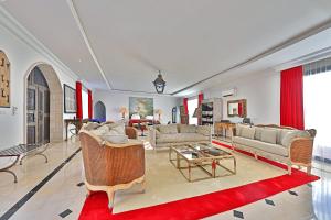 ein großes Wohnzimmer mit Sofas und einem roten Teppich in der Unterkunft DAR OOMI in Zarzis