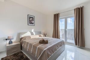 een witte slaapkamer met een bed en een raam bij Terrace View - Stylish Two Bedroom Penthouse in Msida