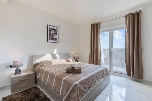 a white bedroom with a bed and a window at Terrace View - Stylish Two Bedroom Penthouse in Msida