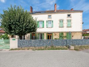 una casa blanca con una valla de piedra y un árbol en Gite de l'Arboretum, en Dompierre-les-Ormes
