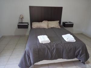 a bedroom with a large bed with two towels on it at Nueva Era Apart in La Consulta