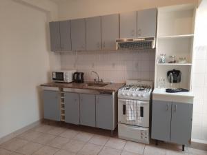 eine Küche mit weißen Schränken und einer Spüle und einem Herd in der Unterkunft Departamento Coronel Arias in San Salvador de Jujuy