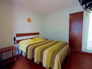 um quarto com uma cama com um cobertor listrado amarelo e preto em LAS PALMERAS HOSTAL em Barranca