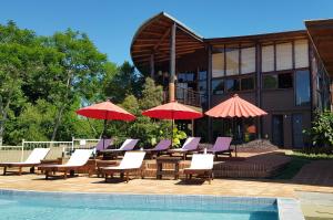 艾索貝比歐的住宿－Puro Moconá Lodge，一组椅子和遮阳伞,位于游泳池旁