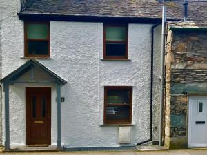 a white house with three windows and a door at Fern Cottage in Ambleside