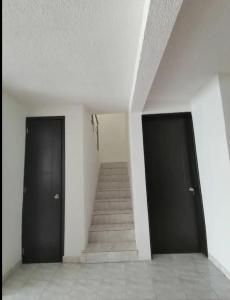 a hallway with two black doors and a staircase at Hogar amplio y acogedor in Ixmiquilpan
