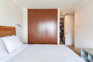 a bedroom with a large bed with a wooden door at Century View 2B W/Balcony, View & Parking. in Santiago