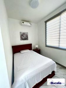 a bedroom with a white bed and a window at Bucalia House Machala in Machala