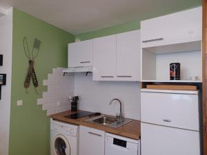 a kitchen with white cabinets and a washing machine at REL'AX - T2 - Plein coeur Ax - Literie de qualité - Wifi - 200m télécabine in Ax-les-Thermes