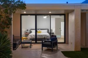 een slaapkamer met een bed en 2 stoelen op een patio bij The Sunset House Pool & Spa in Palm Springs